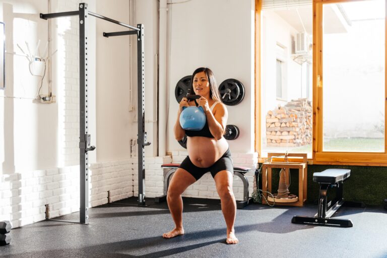 Pregnant Chinese Woman Performing Kettlebell Squats in a Bright Home Gym During Morning Exercise Routine